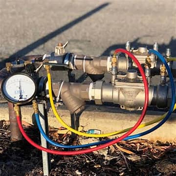 Backflow prevention assembly with pressure gauge and test hoses outdoors